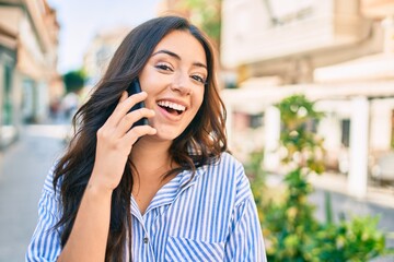 Young hispanic businesswoman smiling happy talking on the smartphone at the city.