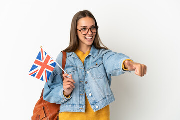 Young hispanic woman holding an United Kingdom flag over isolated white background giving a thumbs up gesture