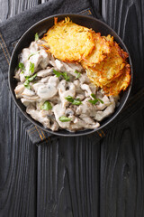 Zurich Ragout or Zürcher Geschnetzeltes Swiss simple ragout or stew recipe in a white sauce is made with mushrooms and white wine closeup in the plate. Vertical top view