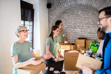 Group of volunteers with working in community charity donation center.