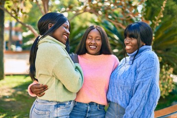 Three african american friends smiling happy hugging at the park.