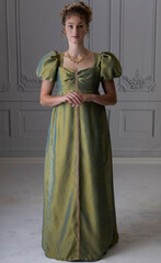 A young Regency woman wearing a green shot silk dress and shown from in front of 3/4 view