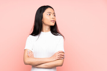 Teenager Chinese woman isolated on pink background looking to the side