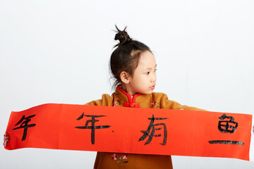Cute Asian little girl writing the word blessing. Chinese New Year's festive decorations