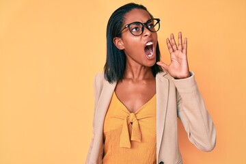 Young african american woman wearing business clothes shouting and screaming loud to side with hand on mouth. communication concept.