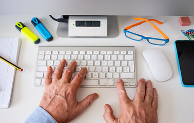 Male hands work on the computer keyboard - white desk