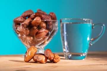 Muslim iftar or breaking of fast food during Ramadan month with close-up on preserved sweet dates. Bowl of dates and water as background.