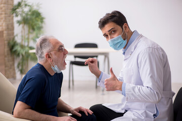 Fototapeta premium Old male patient visiting young male doctor otorhinolaryngologis