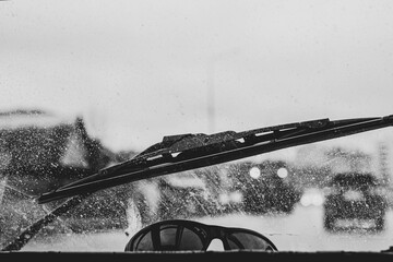 the view from the car interior through the dirty windshield during the rain, on the road in difficult meteorological conditions, the front and back backgrounds are blurred with the bokeh effect
