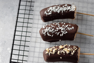 Bananas in dark chocolate with toppings on stick. Frozen healthy dessert. close-up