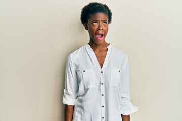 Young african american girl wearing casual clothes angry and mad screaming frustrated and furious, shouting with anger. rage and aggressive concept.