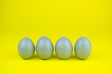 Four eggs in a trendy trendy gray stand against a yellow background. Easter, painting eggs for the event
