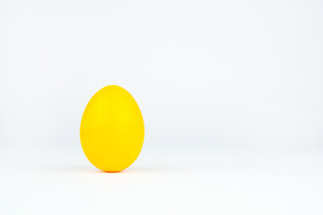 Yellow easter egg isolated on white background. Chicken egg painted in yellow color stands on surface, close up. Object for design to easter holiday