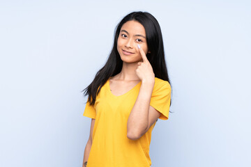 Teenager Chinese woman isolated on blue background showing something