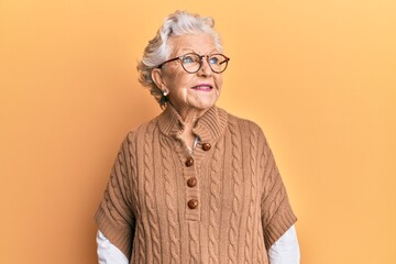 Senior grey-haired woman wearing casual clothes and glasses smiling looking to the side and staring...