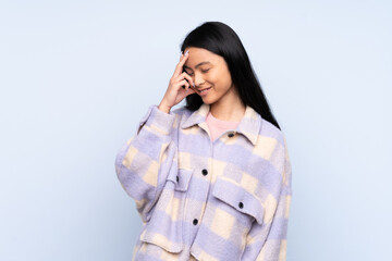 Teenager Chinese woman isolated on blue background laughing