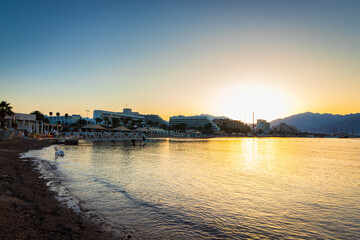 Fototapeta premium The beach in Eilat, empty of people at sunrise, in the background of the hotels and the promenade, Israel