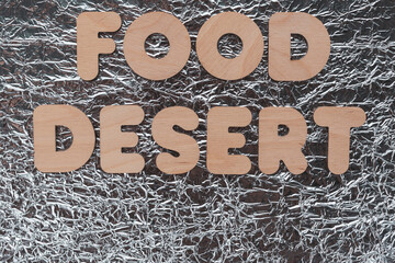 Text - food desert. Wooden letters. The background is a shiny material with highlights. The concept of an area that has limited access to affordable and nutritious food.
