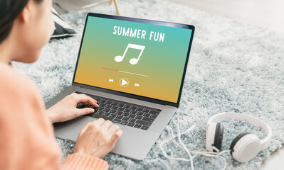 Modern teenagers listening to music with an application from the laptop via the Internet online.