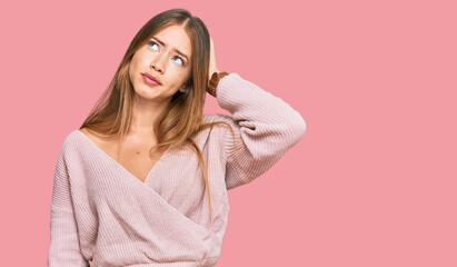 Beautiful blonde woman wearing casual winter pink sweater confuse and wondering about question. uncertain with doubt, thinking with hand on head. pensive concept.