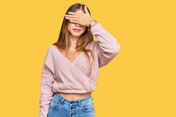 Beautiful blonde woman wearing casual winter pink sweater covering eyes with hand, looking serious and sad. sightless, hiding and rejection concept