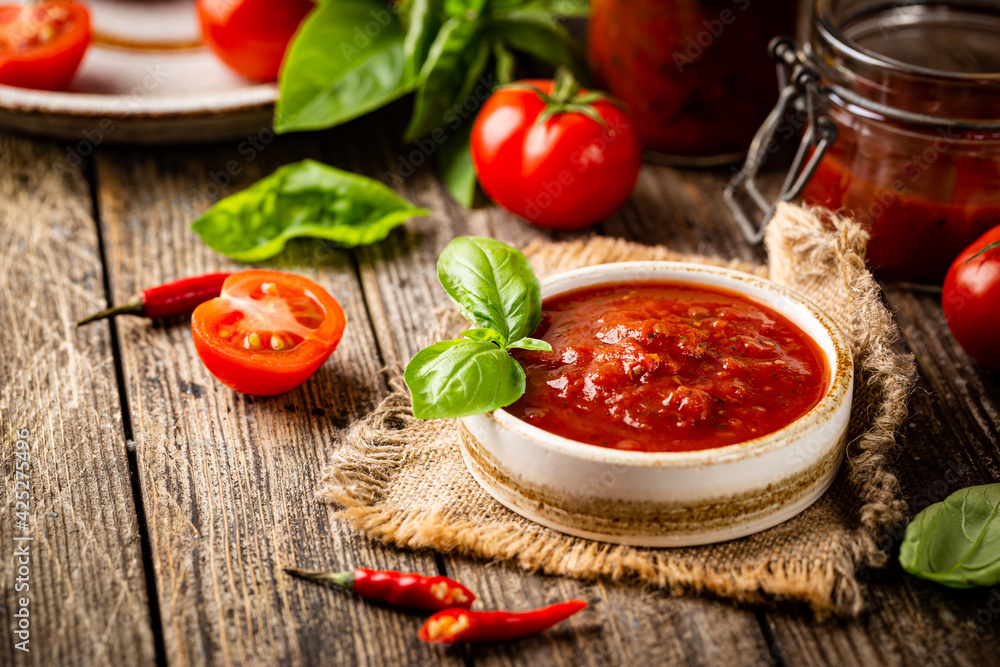 Poster bowl of italian tomato sauce with basil and fresh tomatoes on wooden background