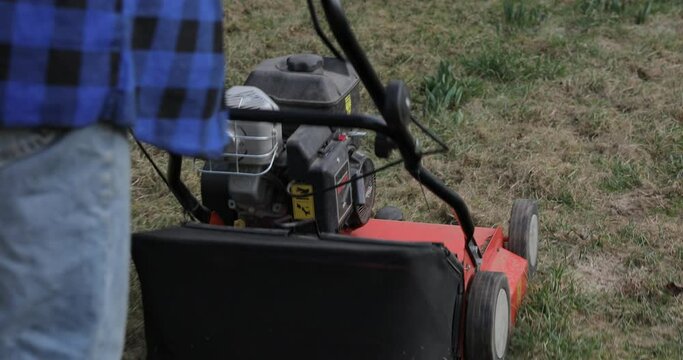Man using gas powered aerating machine to aerate residential grass yard. Preparing the lawn for summer with an aerator in early spring. Garden machines concep