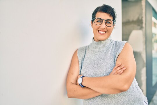 Young plus size woman smiling happy leaning on the wall at the city.