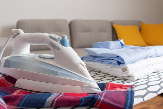 Steam blue iron on ironing board. Clothes, ironing board household concept