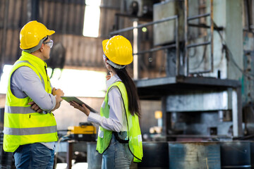 Manufacturing Factory man and woman Mechanical Engineer Works on digital tablet at Metal lathe industrial manufacturing factory. Engineer Operating lathe Machinery