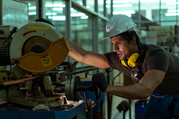 Technician engineer wearing hard hat maintenance the metal cutting machine in the factory. Industry male worker control machines in the workplace on a business day. Concept of Industrial manufacturing