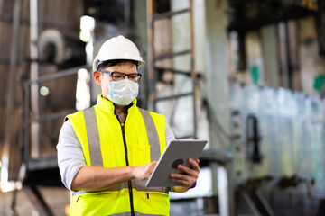 Worker man wearing face mask prevent covid-19 virus and protective hard hat. Engineer Operating lathe Machinery.