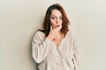 Young caucasian woman wearing casual clothes looking fascinated with disbelief, surprise and amazed expression with hands on chin