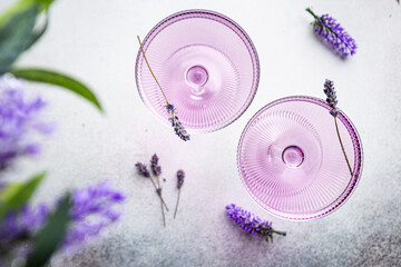 Purple cocktail drink in a glass on white background with flowers, top view