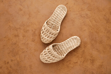 Comfortable and stylish home or beach slippers made of natural tropical rattan. Brown background....