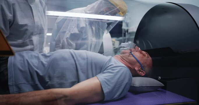 Doctors discussing aged man in hyperbaric chamber