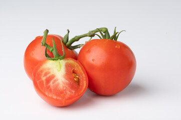 Fresh tomatoes on a green stem on white