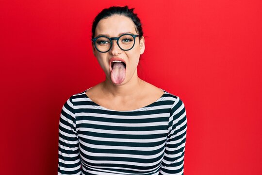 Young caucasian woman wearing casual clothes and glasses sticking tongue out happy with funny expression. emotion concept.