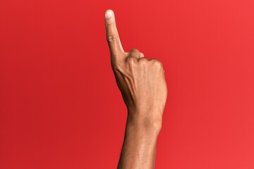 Hand of hispanic man over red isolated background counting number one using index finger, showing idea and understanding
