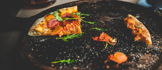 The last slice of pizza on black wooden board in cafe
