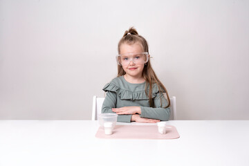 Laboratory, chemical experiments day 2 of 14. A pretty girl, with plastic goggles, in a green...