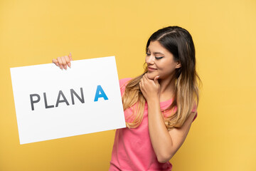 Young Russian girl isolated on yellow background holding a placard with the message PLAN A and thinking