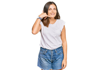 Young caucasian woman wearing casual white tshirt smiling doing phone gesture with hand and fingers like talking on the telephone. communicating concepts.