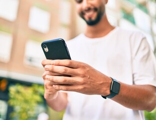 Young arab man smiling happy using smartphone at the city.