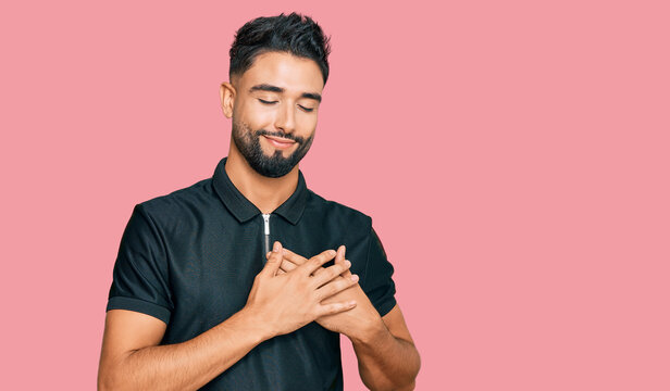 Young man with beard wearing sportswear smiling with hands on chest with closed eyes and grateful gesture on face. health concept.