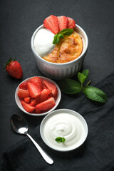 Cottage cheese casserole with strawberries and mint on a dark background.