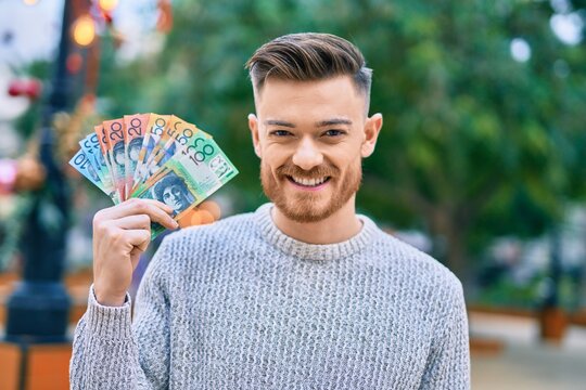 Young caucasian man smiling happy holding australian dollars at the park.