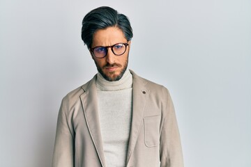 Young hispanic man wearing business jacket and glasses skeptic and nervous, frowning upset because...