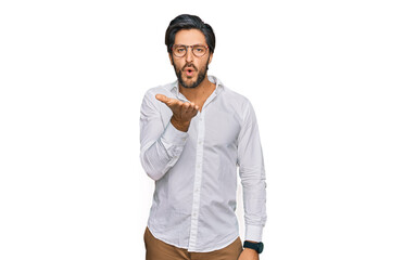 Young hispanic man wearing business shirt and glasses looking at the camera blowing a kiss with hand on air being lovely and sexy. love expression.