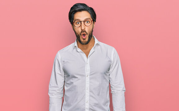 Young hispanic man wearing business shirt and glasses afraid and shocked with surprise expression, fear and excited face.